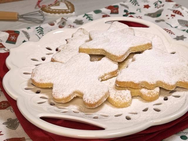 paste frolle di Santa Lucia con zucchero a velo nel vassoio bianco sulla tovaglia natalizia