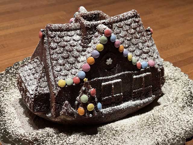 torta a forma di casetta di natale decorata con confetti colorati