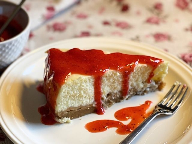 Fetta di New York cheesecake vegana cotta al forno con salsa alle fragole