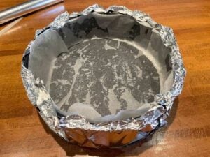 Tortiera rivestita con alluminio pronta per la cottura della cheesecake vegana