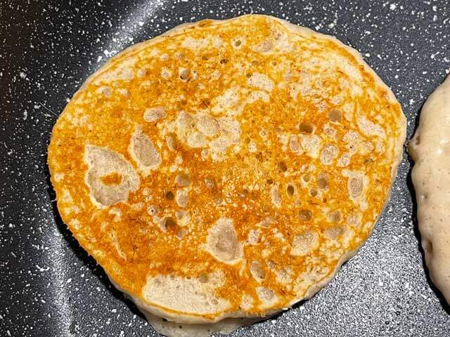 Pancake alla banana senza uova dorato durante la cottura in padella.