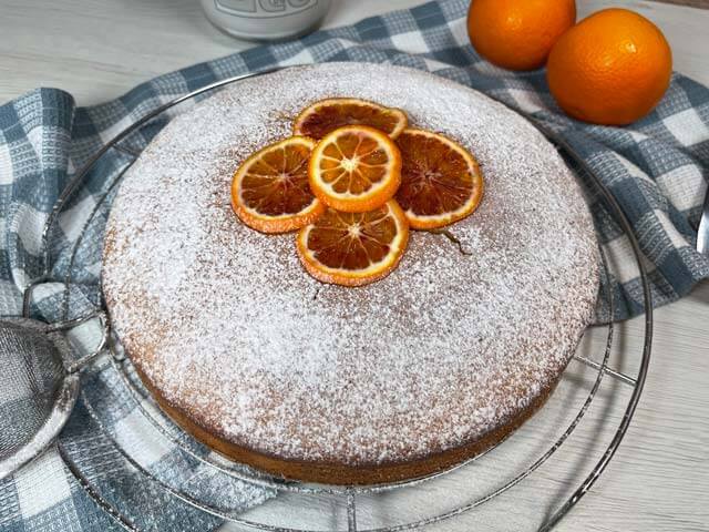 torta all'arancia vegana decorata con zucchero a velo e fette d'arancia
