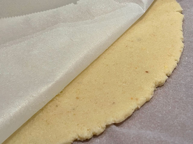 pasta frolla alle mandorle stesa tra due fogli di carta forno