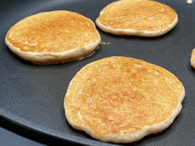 Pancake vegani dorati dopo essere stati girati in padella durante la cottura.