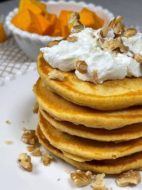 pancakes alla zucca dorati e impilati con sciroppo d'acero, noci e yogurt
