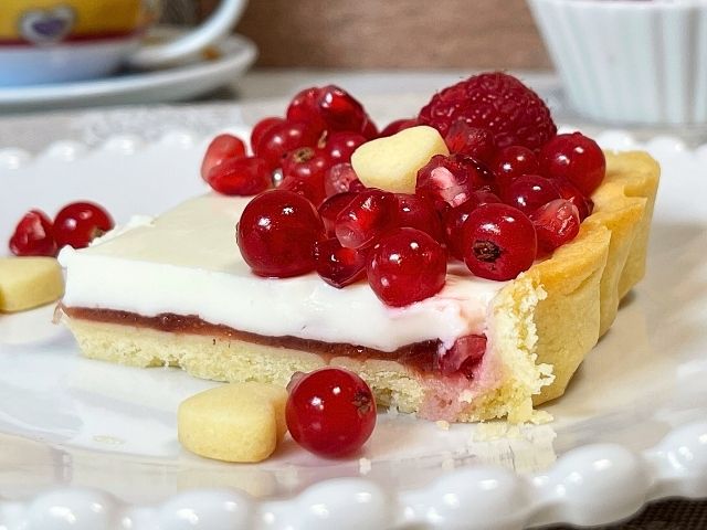 fetta di crostata di frutta a forma di cuore decorata con frutti rossi