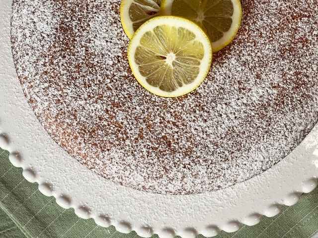 torta al limone senza glutine decorata con fette di limone e zucchero a velo