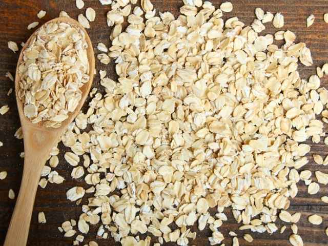 Fiocchi di avena con cucchiaio su tavolo in legno