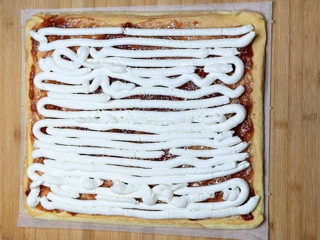 Crema al mascarpone distribuita con la sac à poche sulla confettura di fragole
