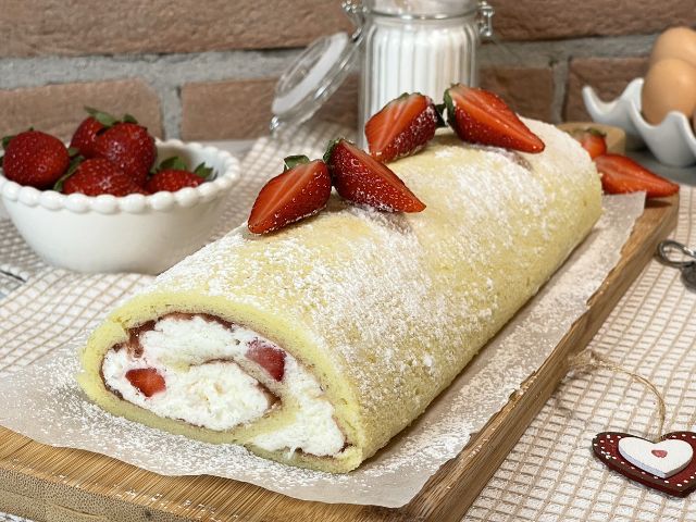 Rotolo senza glutine con panna e fragole preparato con pasta biscotto