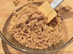 Biscotti tritati mescolati con burro fuso per la base della cheesecake con ricotta