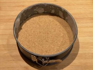 Base di biscotti compattata sul fondo della tortiera a cerniera per cheesecake con ricotta