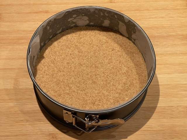 Base di biscotti compattata sul fondo della tortiera a cerniera per cheesecake con ricotta