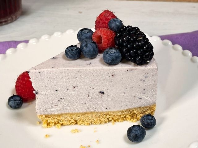 Fetta di cheesecake con ricotta senza cottura decorata con frutti di bosco freschi