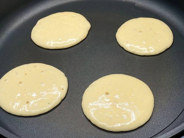 Pancake in cottura con le bollicine in superficie prima di essere girati.