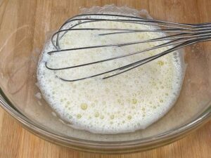 Uovo e zucchero mescolati con una frusta a mano.