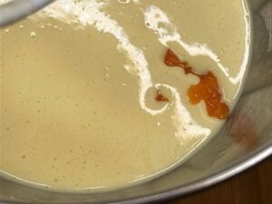 Aggiunta della purea di zucca al composto di uova, zucchero e olio per la ciambella senza glutine.