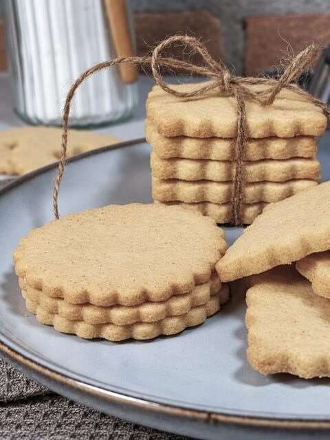 Biscotti di pasta frolla dorati impilati su un piatto e legati con uno spago.