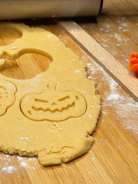 Pasta frolla alla zucca senza glutine stesa con il mattarello per preparare biscotti