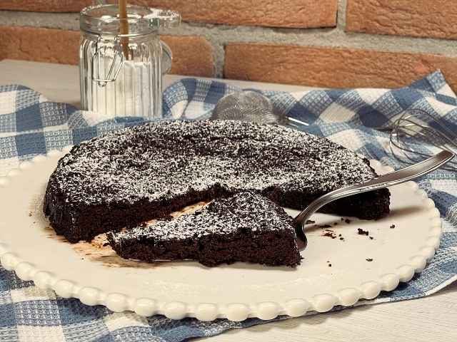 torta tenerina vegana senza uova al cioccolato spolverata con zucchero a velo